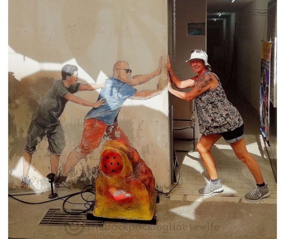 Backpacking Housewife. Two guys are pushing a door. This mural is located next to Penang umbrella street