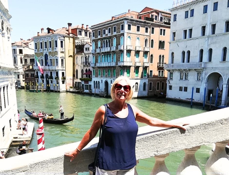 Janice Horton standing on a bridge over a canal and enjoying Venice